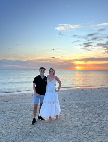Nina and Javi barefoot on a beach at golden-hour sunset in the Algarve